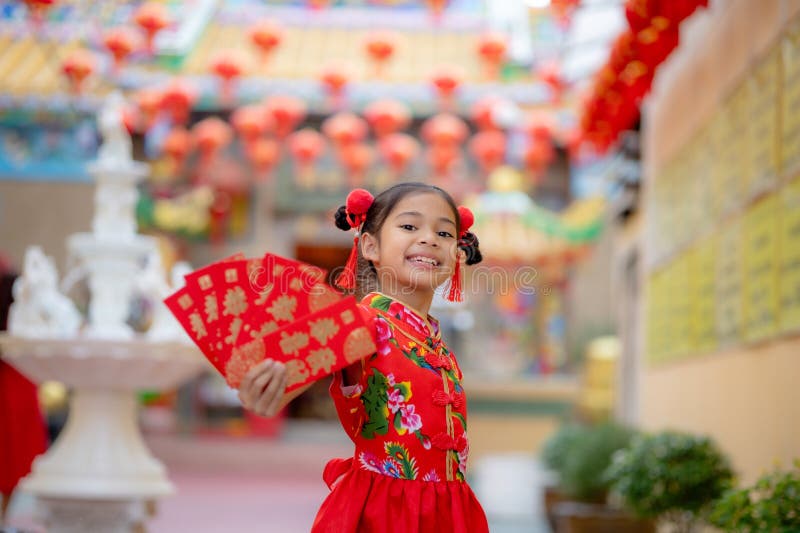 Asian girl wearing red traditional Chinese cheongsam decoration holding red envelopes in hand and lanterns with the Chinese text stock photo