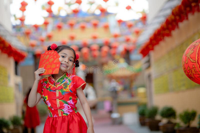 Asian girl wearing red traditional Chinese cheongsam decoration holding red envelopes in hand and lanterns with the Chinese text royalty free stock photo