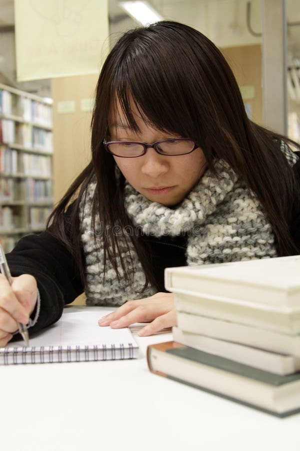 An Asian girl who is reading and studying