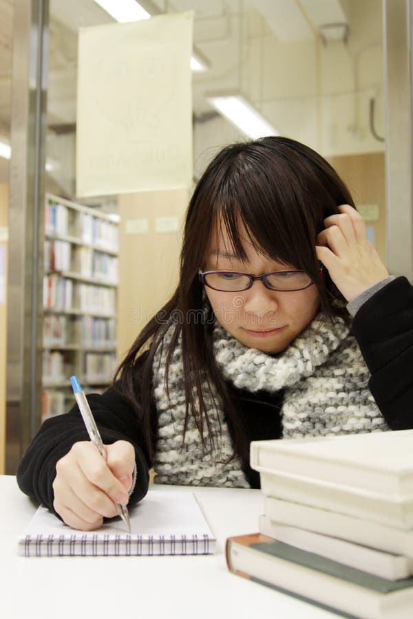 An Asian girl who is reading and studying