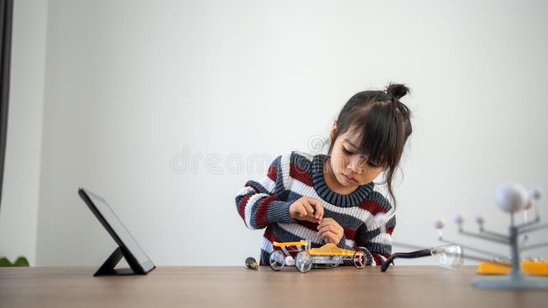 Asian girls enjoy making and fixing electrical robot car and learning online tutor training course stock photos