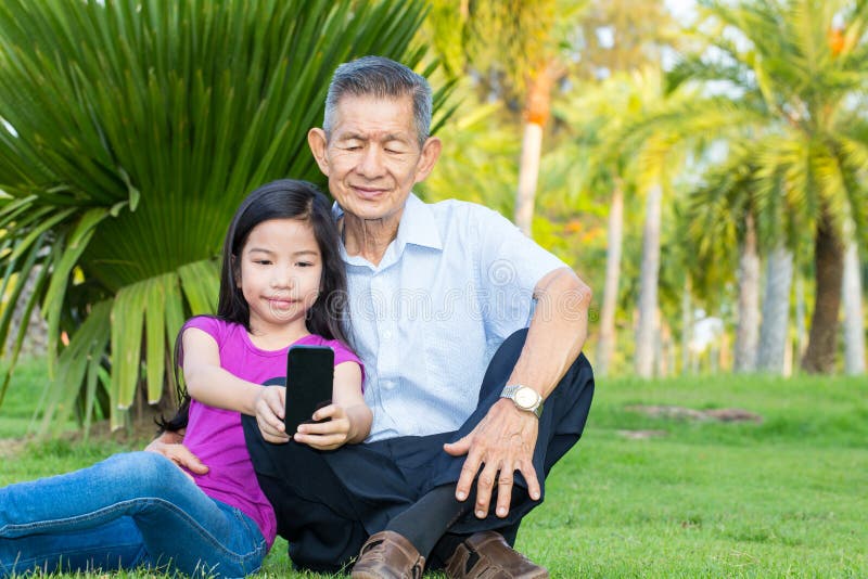 Asian grandfather and grandchild taking selfie with smartphone royalty free stock image Asian grandfather and grandchild taking selfie with smartphone royalty free stock image