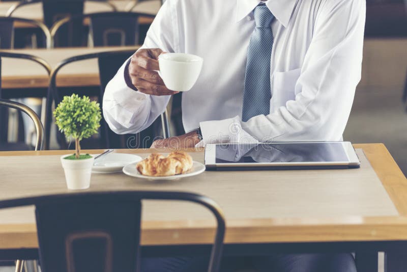 Asian Handsome businessman working outdoor in the coffee shop with laptop and holding cup of coffee on hand. Work outside office