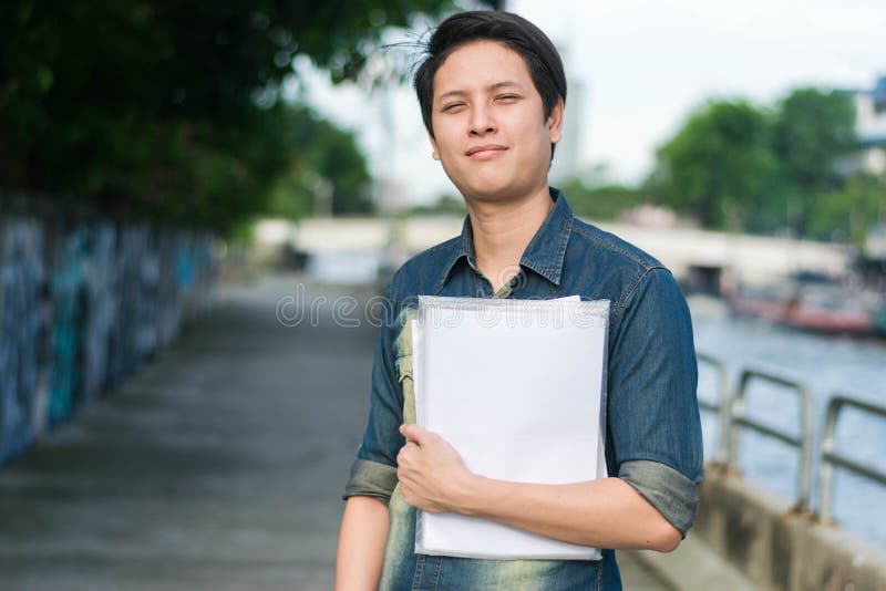 Asian happy man standing and holding document files in arms. Asian happy man standing and holding document files in arms