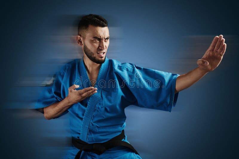 Я спешу на тренировку в кимоно сражаюсь. Азиат каратист. Каратист казашка. Каратист спортсмена на синем фоне. Мужчина в кимоно дерется.