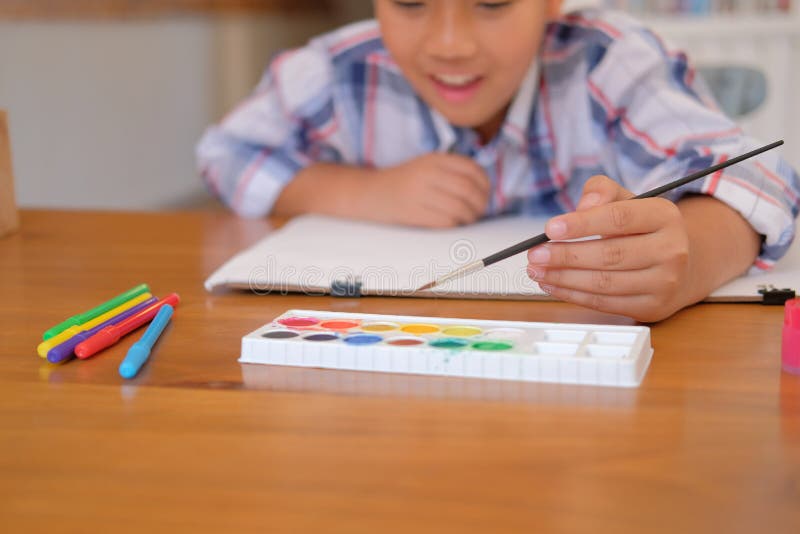 Asian kid boy child schoolboy holding paint brush drawing painting watercolor. children leisure activity at home stock photo Asian kid boy child schoolboy holding paint brush drawing painting watercolor. children leisure activity at home stock photo