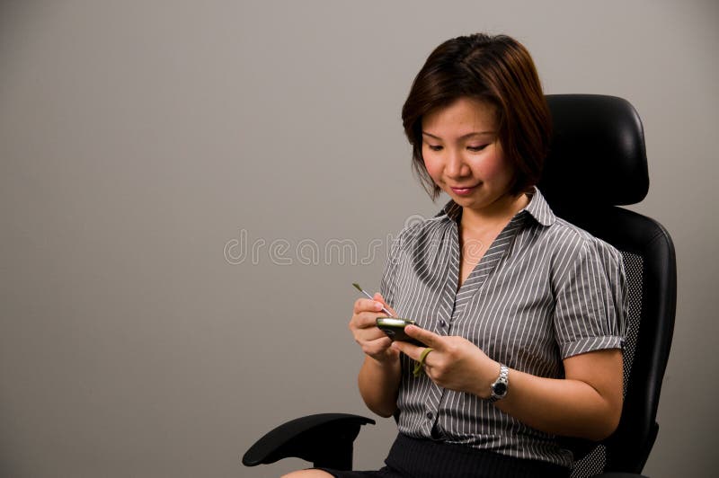 Asian lady in business attire, using a PDA