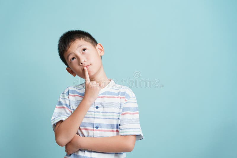 Asian little boy standing thinking on blue background isolated, Asia man look up and copy space