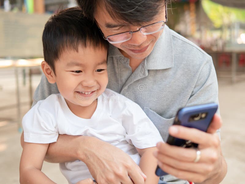 Asian little child boy watching smart phone with dad with happy smiling face. stock images Asian little child boy watching smart phone with dad with happy smiling face. stock images