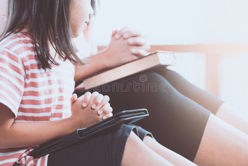 Cute asian little child girl and her mother praying with folded hands in the room for faith,spirituality and religion concept