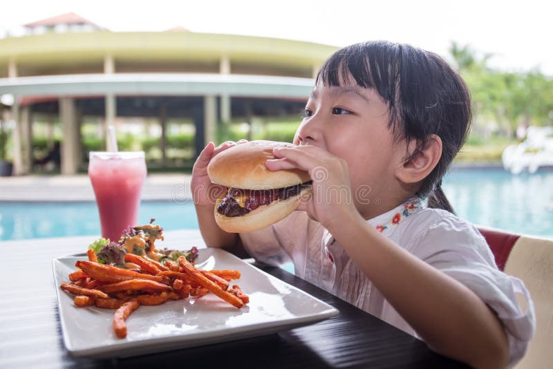 Asian Little Chinese Girl Eating Burger and French fries