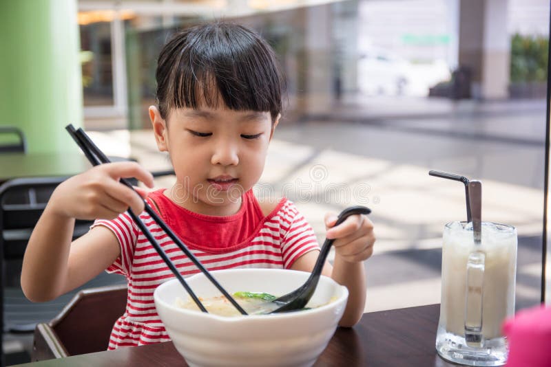 Asian little Chinese girl eating noodles soup