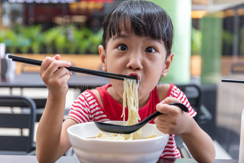 Asian little Chinese girl eating noodles soup