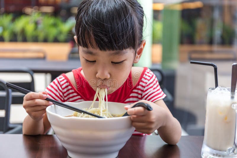 Asian little Chinese girl eating noodles soup