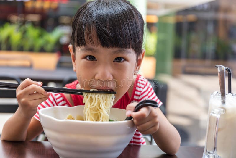 Asian little Chinese girl eating noodles soup