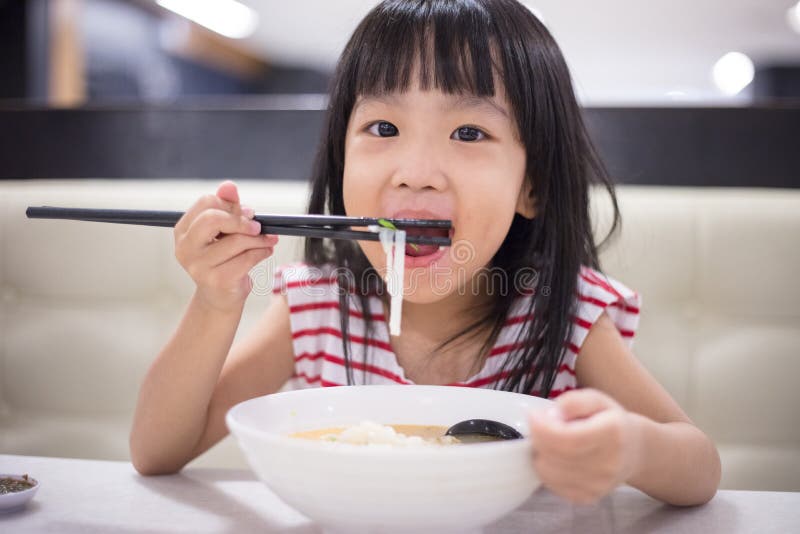 Asian little Chinese girl eating noodles soup