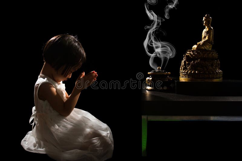 Asian Little Chinese Girl Praying in front of Buddha in isolated Black Background