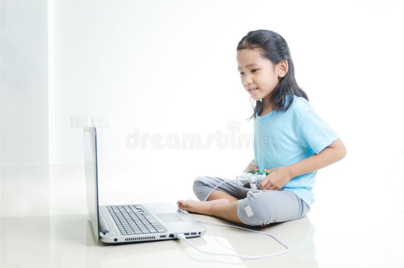 Asian Little Girl Playing Games with Laptop Computer and Joystick
