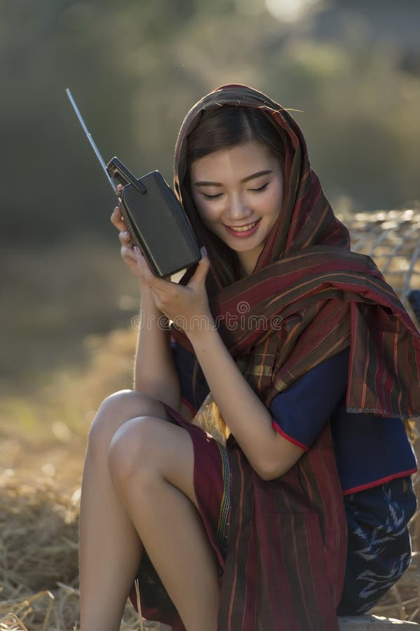 Femeie frumoasă din Asia ascultând la radio pe paie royalty free stock photos