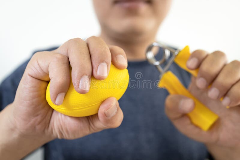 Asian male patient doing hand,finger and wrist exercise with rubber ball and spring hand grip,stretch finger or squeeze with hand