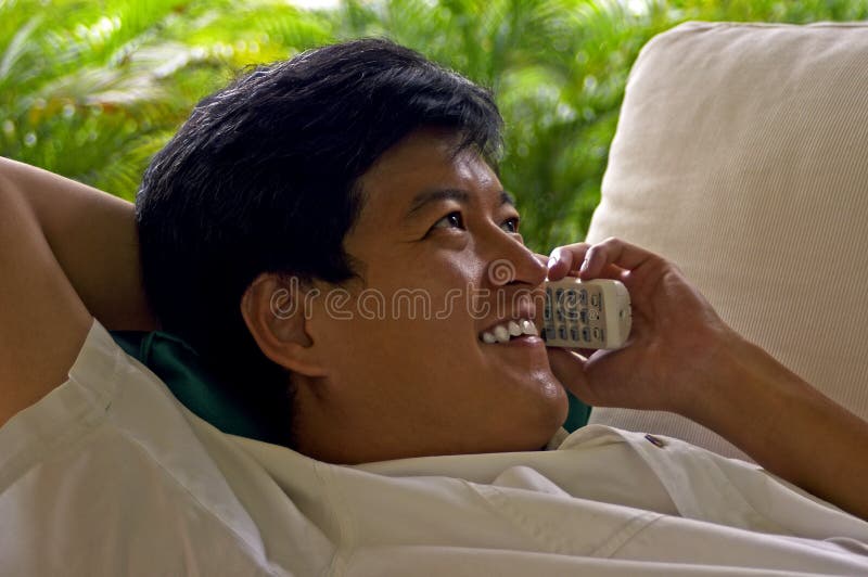 Asian Male Relaxed On The Phone With A Friend royalty free stock photography