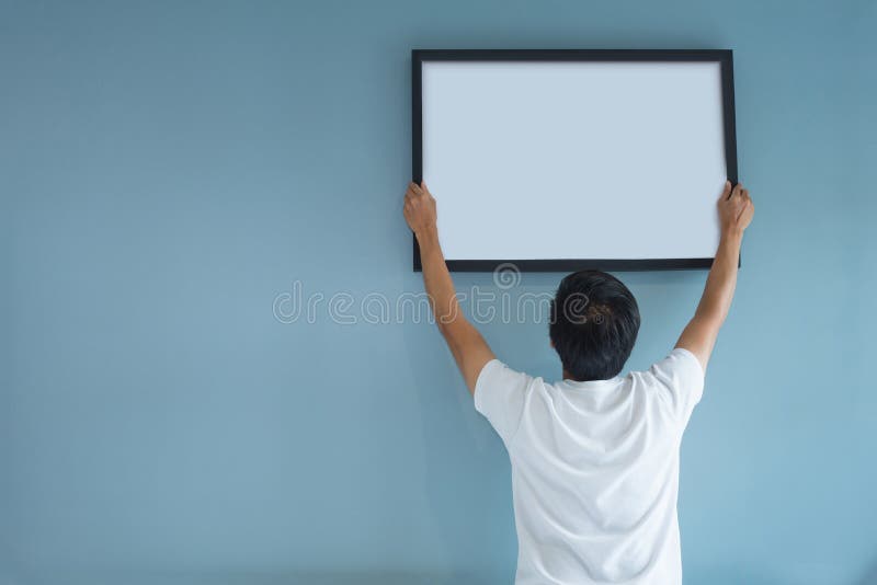 Asian man holding a picture frame on blue wall. royalty free stock image Asian man holding a picture frame on blue wall. royalty free stock image