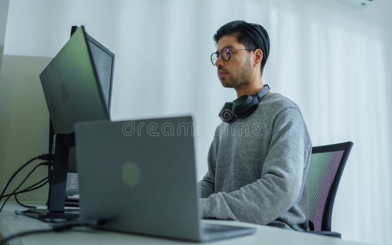 Asian man prompt engineer develop coding app with software data sitting in front of computer monitor at office.