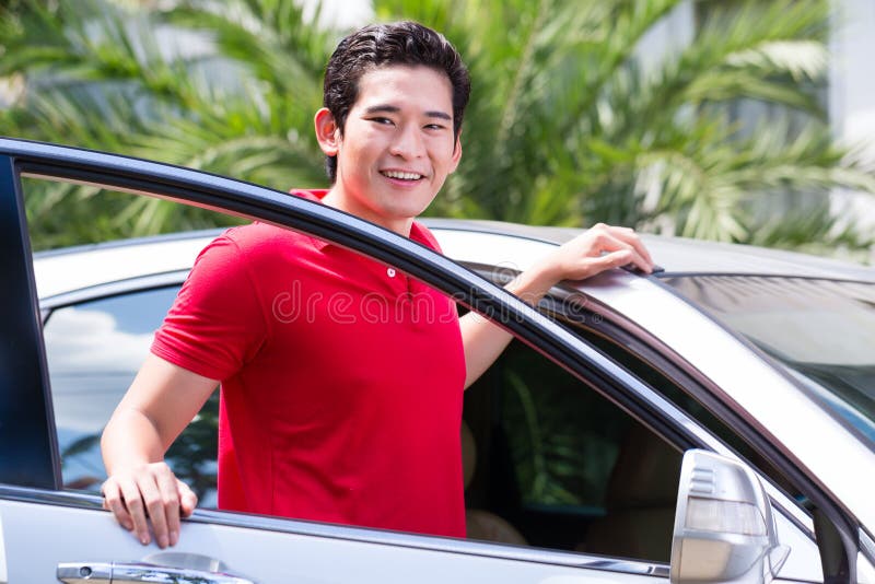 Asian man standing in front of car