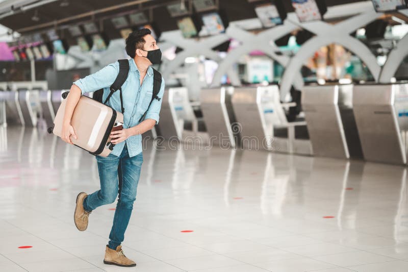 Asian man wearing protective face mask running at airport