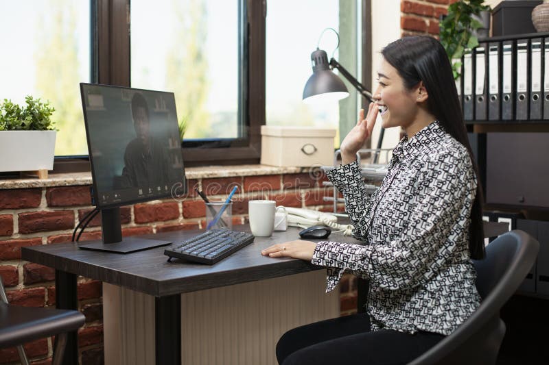 Asian manager waves in virtual meeting stock photography