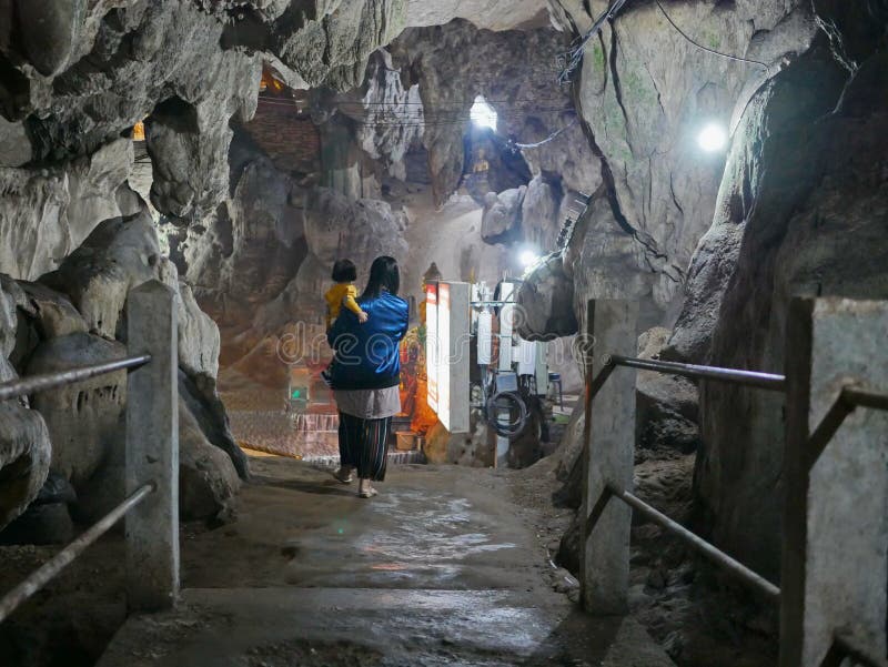 Asian mother carrying her little baby girl walking deep inside of a cave with lighting provided for visibility royalty free stock images Asian mother carrying her little baby girl walking deep inside of a cave with lighting provided for visibility royalty free stock images