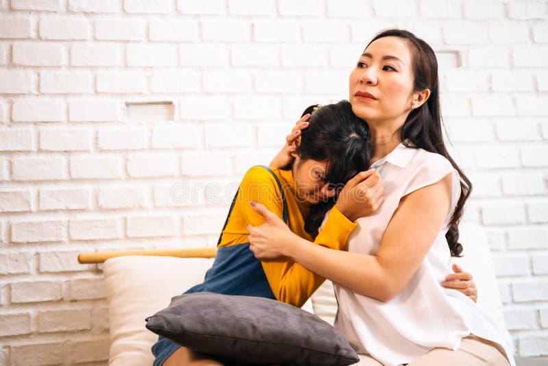 Asian mother comforting crying teenage daughter in miserable, stressed, depressed, sad state of mind