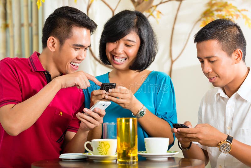 Asian people having fun together with mobile phone and drinking coffee or cocktail. Asian people having fun together with mobile phone and drinking coffee or cocktail