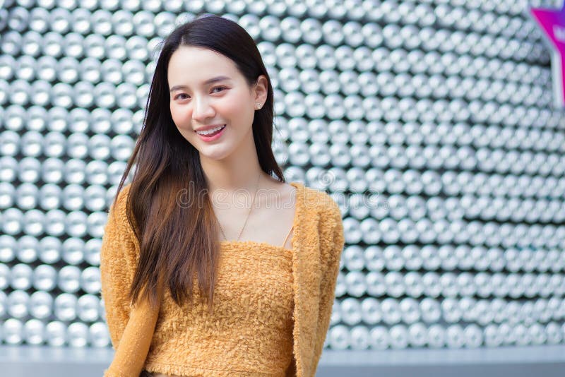 Asian pretty woman in long hair wears a yellow sweater and brightly smiles in Valentineâ€™s theme.