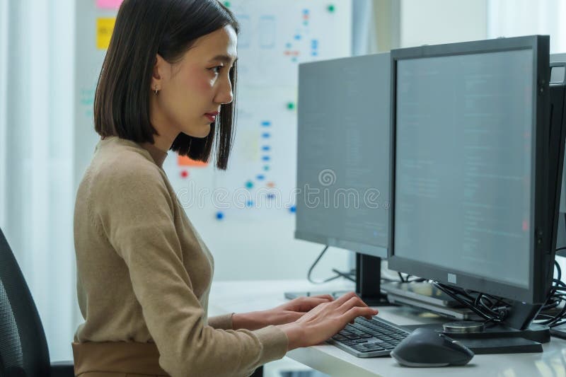 Asian prompt engineer develop coding app with software data sitting in front of computer monitor at office stock image