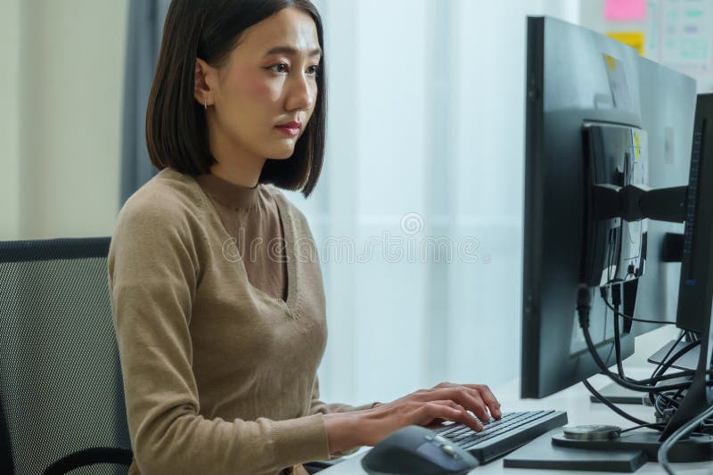 Asian prompt engineer develop coding app with software data sitting in front of computer monitor at office royalty free stock images