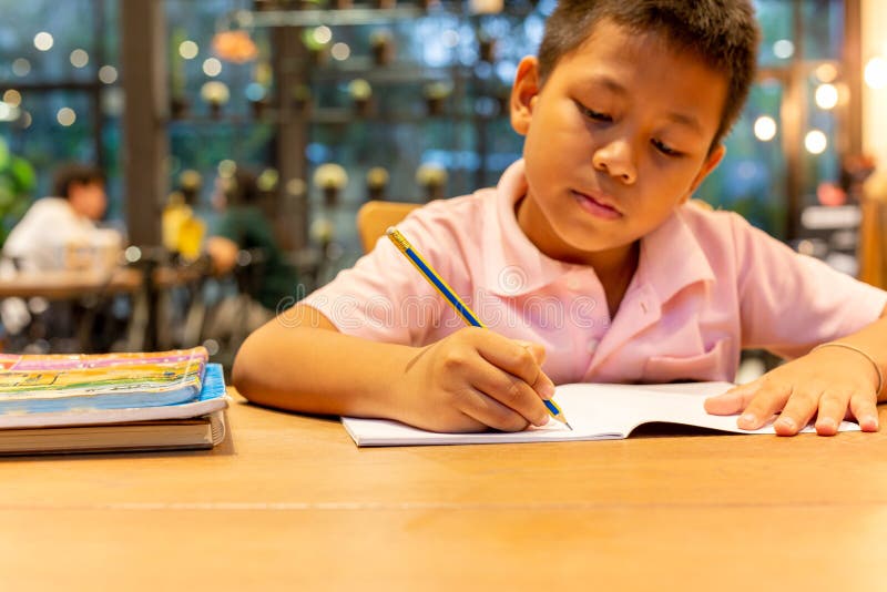 Asian Schoolboy Hand With Pencil Doing His Homework At Home Stock