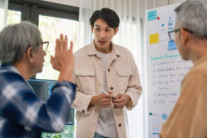 Asian senior bootcamp team asking and learning programming with software training and whiteboard collaboration.