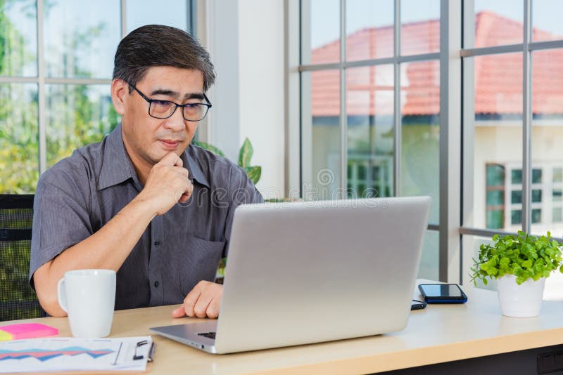 Asian senior business man working online on a modern laptop computer