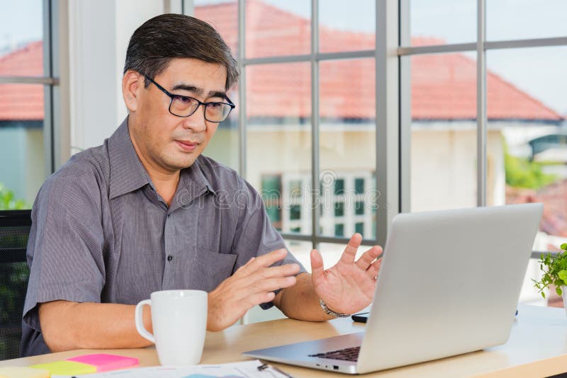 Asian senior business man working online on a modern laptop computer