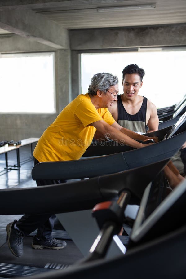 asian Senior men walking exercise on treadmill with Personal trainer workout in fitness gym . sport trainnig , retired , older , mature, elderly , smiling .rehab, rehabilitation, coach, plan, adult, happy, instructor, lifestyle, training, vitality, male, active, health, support, medicare, two, people, young, helping, jogging, determination, retirement, healthy, strong, runner, equipment, 60s, age, cardio, pensioner, wellness. asian Senior men walking exercise on treadmill with Personal trainer workout in fitness gym . sport trainnig , retired , older , mature, elderly , smiling .rehab, rehabilitation, coach, plan, adult, happy, instructor, lifestyle, training, vitality, male, active, health, support, medicare, two, people, young, helping, jogging, determination, retirement, healthy, strong, runner, equipment, 60s, age, cardio, pensioner, wellness