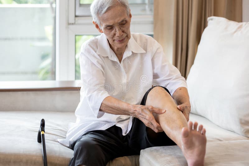 Asian senior woman hold her leg suffering from pain in legs,elderly patient have cramps in her calves,massage the calf by hands or