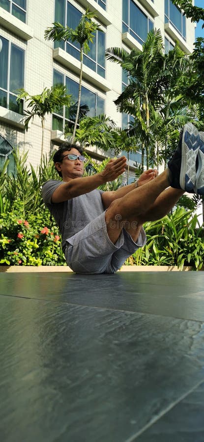 Asian Strong Man Doing Yoga Flexible Balance Exercise In The Park