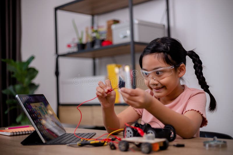 Asian students learn at home by coding robot cars and electronic board cables in STEM, STEAM, mathematics engineering science technology computer code in robotics for kids concepts.