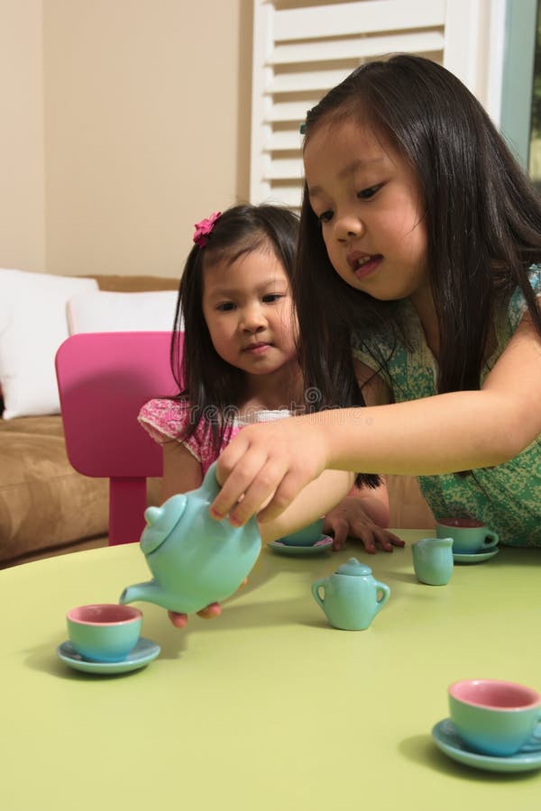 Asian toddlers playing with toy tea set