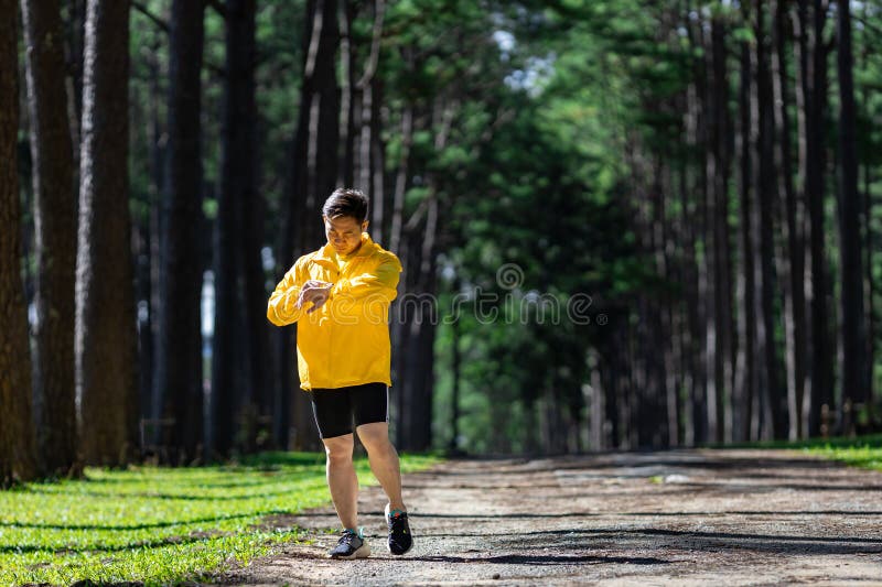 Alergătorul asiatic al pistei se află în aer liber pe șoseaua de pădure de pini, pentru activități de exerciții fizice și de antre stock photo