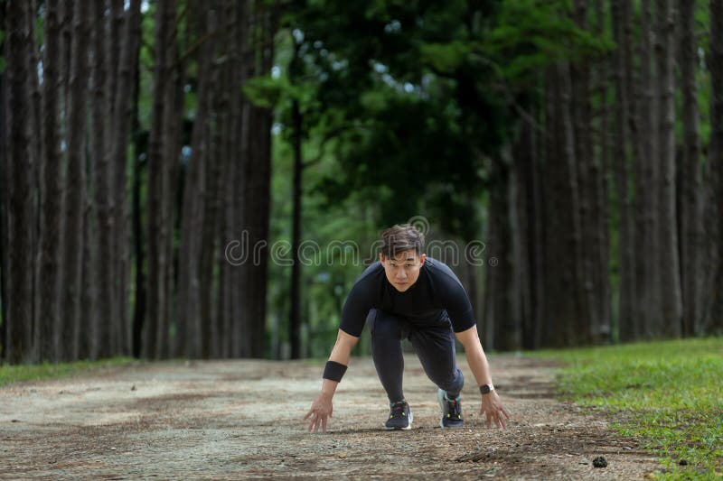 Alergătorul asiatic al pistelor se află în aer liber pe șoseaua pădurii de pin, pentru activități de exerciții fizice și de formar royalty free stock photography