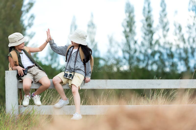 Asian two children raise give me five and sitting on the white fence outdoors, adventure and tourism for destination and leisure t stock image Asian two children raise give me five and sitting on the white fence outdoors, adventure and tourism for destination and leisure t stock image
