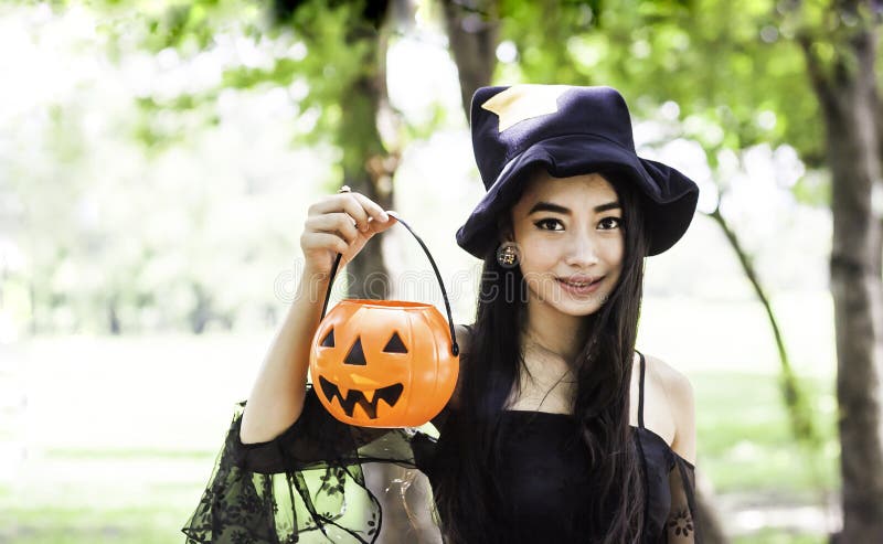 Asian woman on black dress and holding plastic pumpkin doll royalty free stock photography Asian woman on black dress and holding plastic pumpkin doll royalty free stock photography