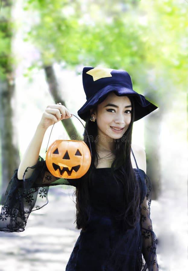 Asian woman on black dress and holding plastic pumpkin doll stock photos Asian woman on black dress and holding plastic pumpkin doll stock photos